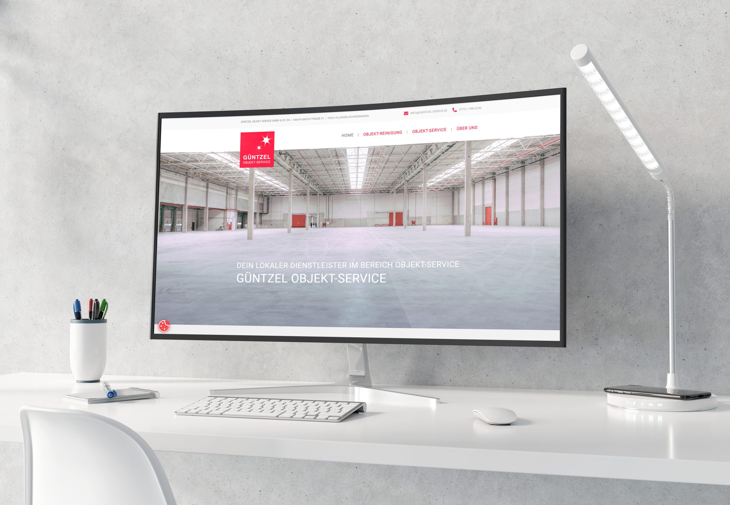 sauberer weißer Schreibtisch mit modernem Monitor Zeigt die Website von Güntzel-Objekt Service
