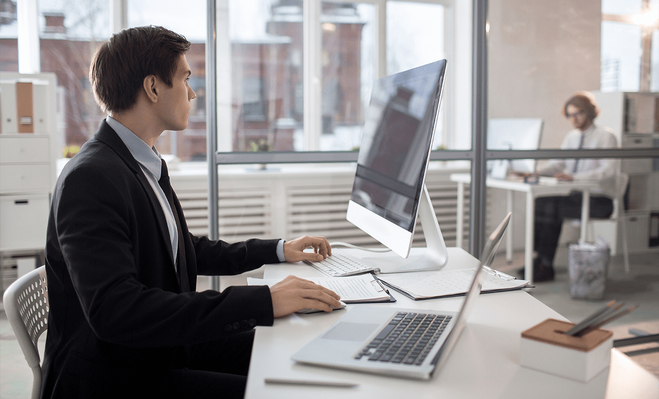 Junger Businessman im Anzug sitzt am Mac