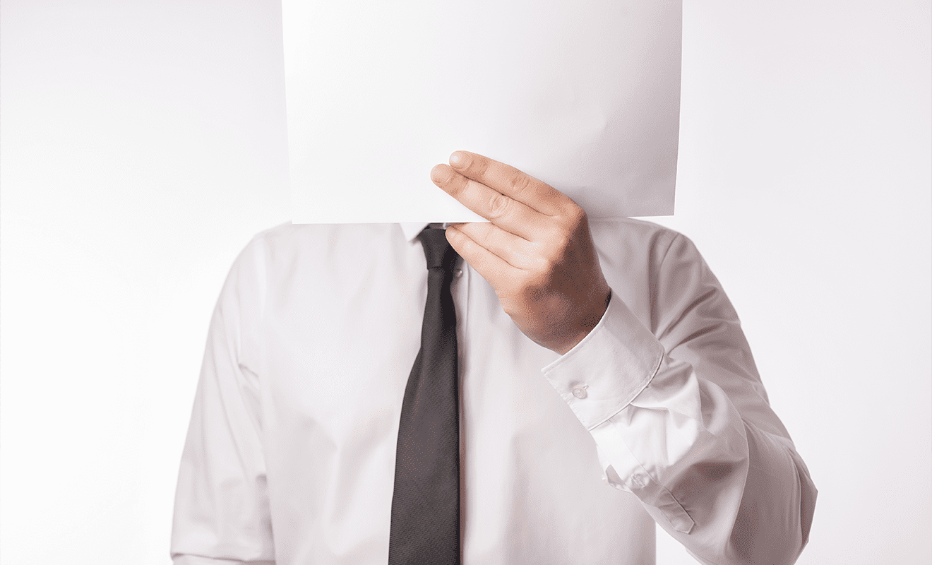 Mann im Anzug hält sich weißes Blatt vors Gesicht